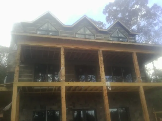 Dormers and porch framing on a large log home under construction — Roof Coating work by our crew in Pembroke